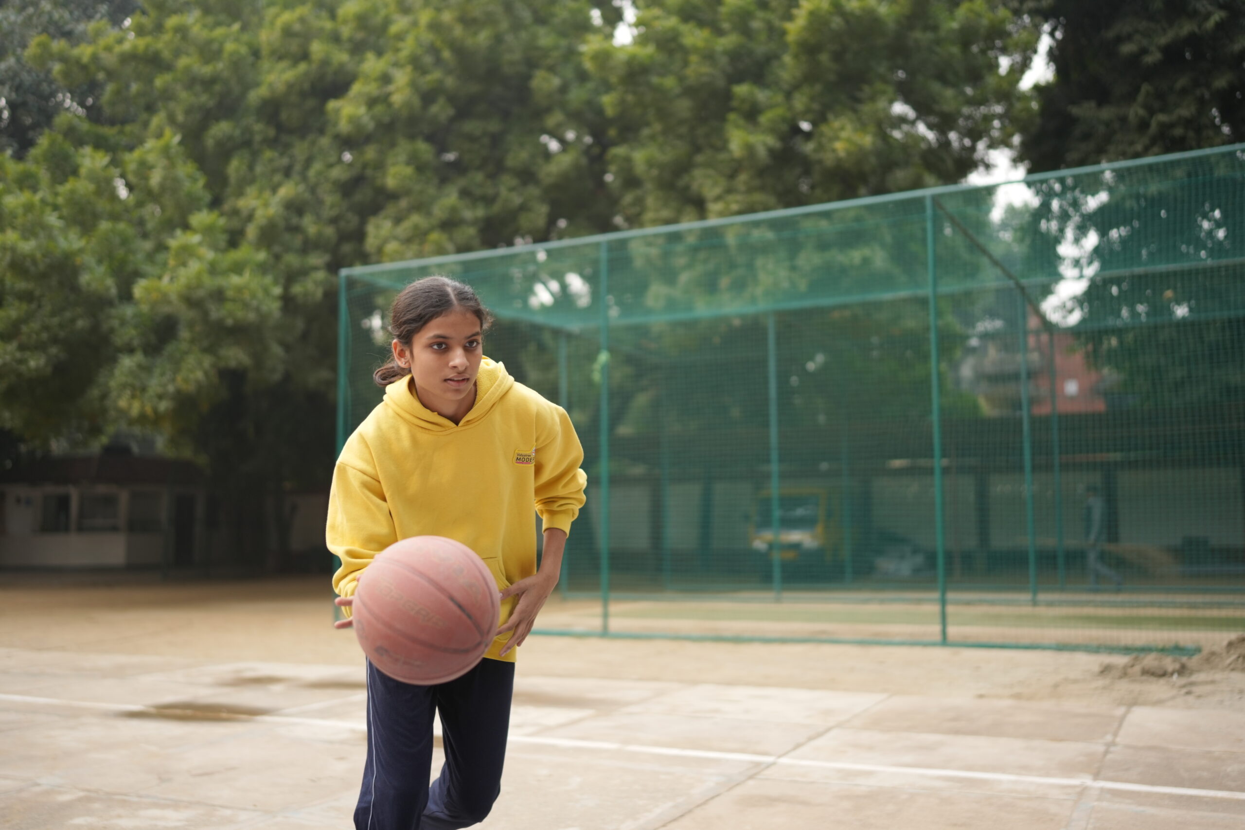 A student playing basketball at Modern School