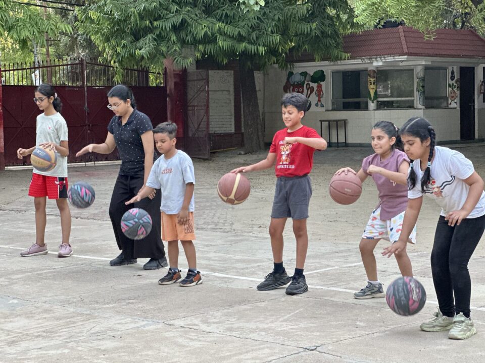 Children dribbling basketballs with a coach